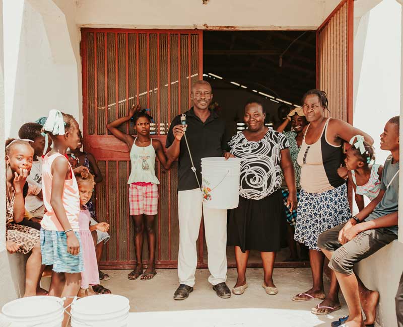Community members with a bucket water filtration system