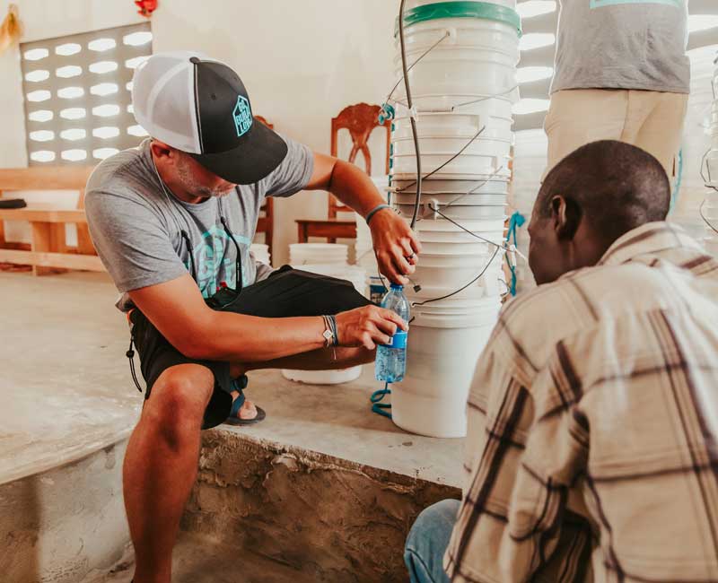 GBL team member demonstrating a bucket water filtration system